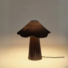 Lade das Bild in den Galerie-Viewer, Schwarze Tischlampe „Uala“ aus feinem Porzellan mit plissiertem Schirm, Design von Sebastian Herkner für Serax. Beleuchtet, auf hellem Hintergrund. Black porcelain table lamp “Uala” with pleated shade